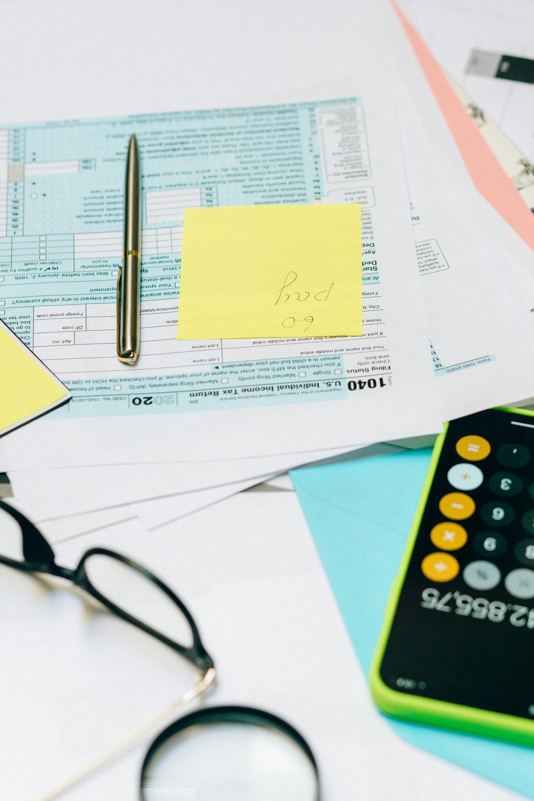 Close-up of tax documents with a calculator, pen, and notes, ideal for financial content.